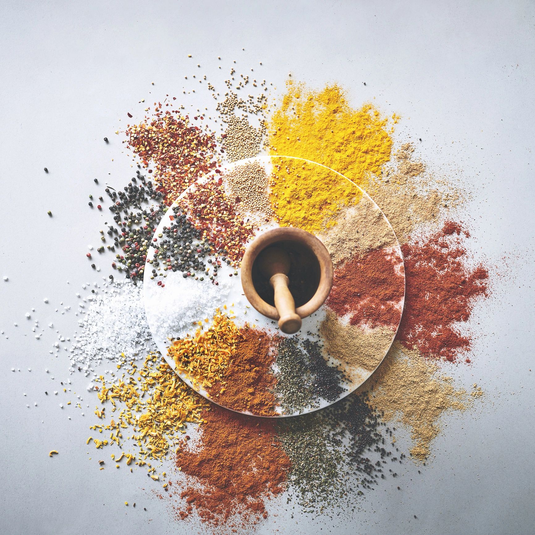 Mortar and pestle with spices scattered on a work surface